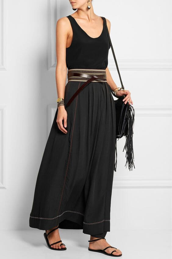 Woman in long silk skirt and simple black vest, together with a strappy leather belt. Black silk skirt and black vests create a nice casual look.