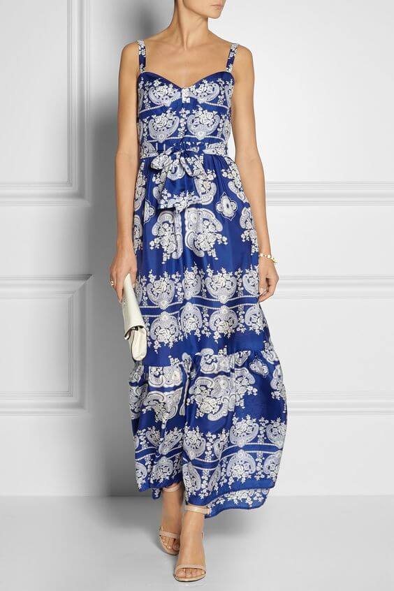 Woman in patterned blue and white dress with white accessories. Real blue elegance: maxi dress & white accessories.