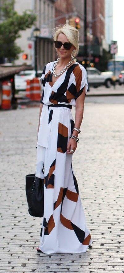 Woman on the street with long white dress with black and brown patterns. White maxi dress with black and brown patterns.