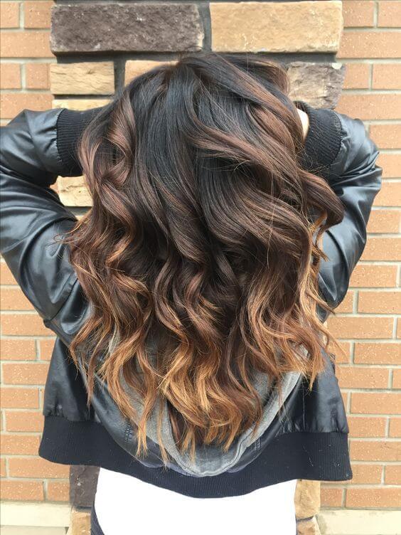 Wavy hairstyle with a gradient from dark brown to golden blonde.