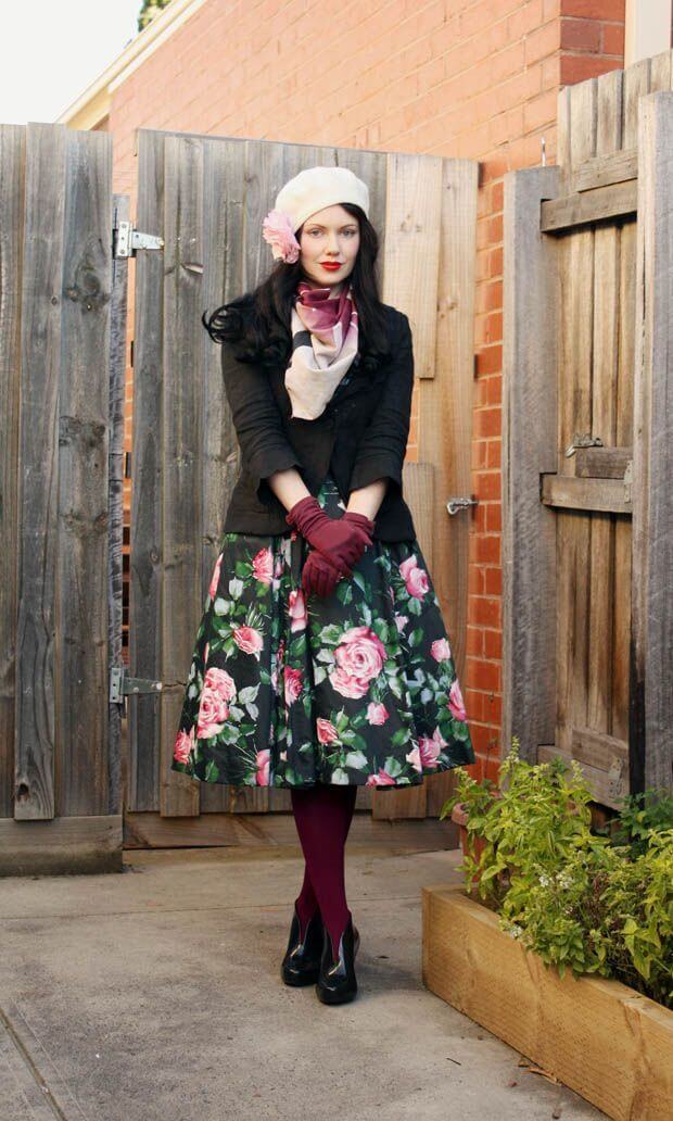 Woman wearing a floral skirt, black jacket, maroon leggings, gloves and a beret