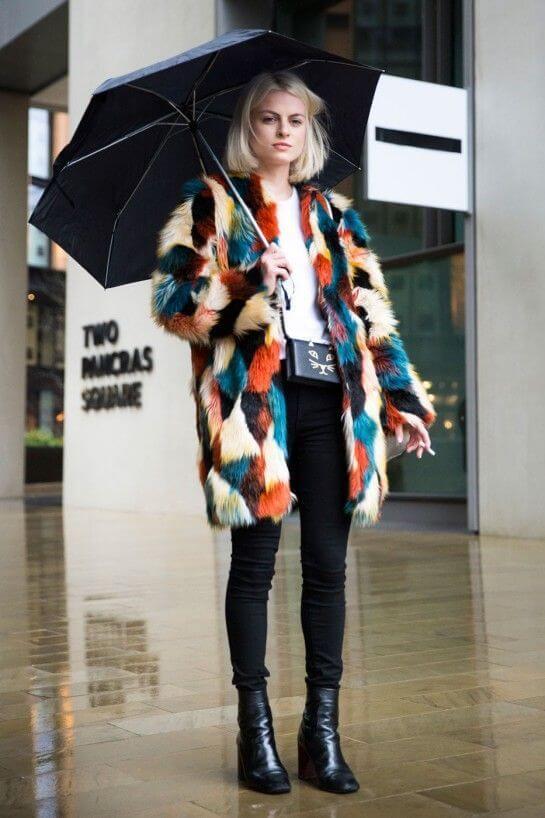 Woman wearing black pants, white tee, and a colorful coat
