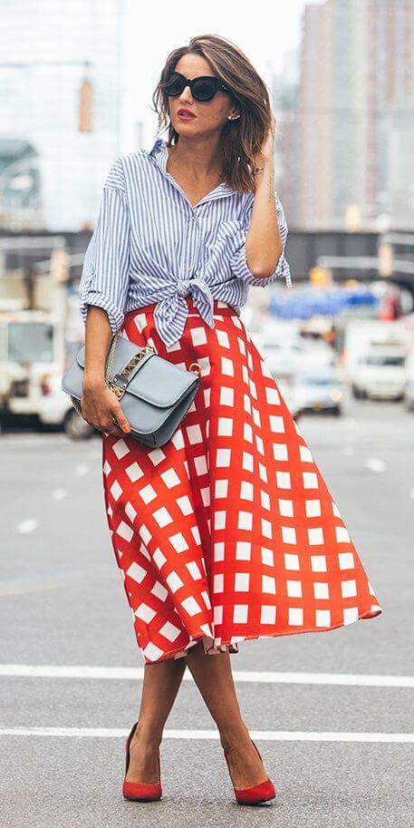 Stylish brunette in check midi skirt and striped shirt. Contrast is king when thin stripes meet a bold check print.
