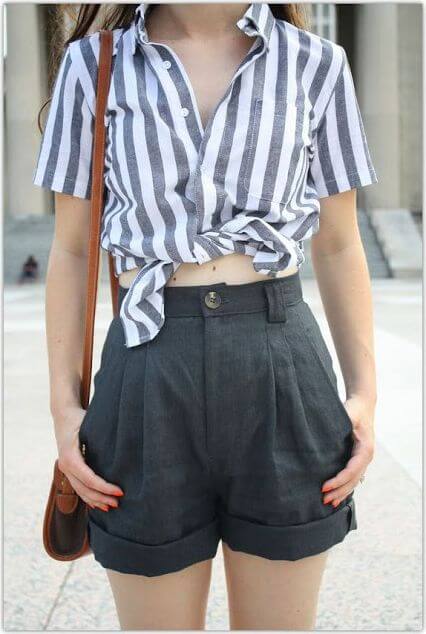 Trendy woman in gray high-waisted shorts and striped shirt. Go back to school in gray pleated shorts and a cheeky knotted striped shirt.