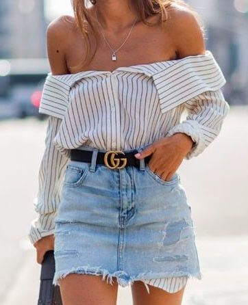 Trendy woman in off-the-shoulder striped shirt and denim skirt
