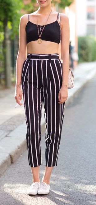 Trendy woman in striped pants and black crop top. Get that sporty effect with vertical stripes and a matching black bralet.