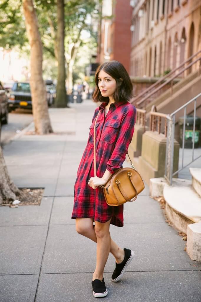 Casually dressed girl in a checked print shirt dress and black sneakers