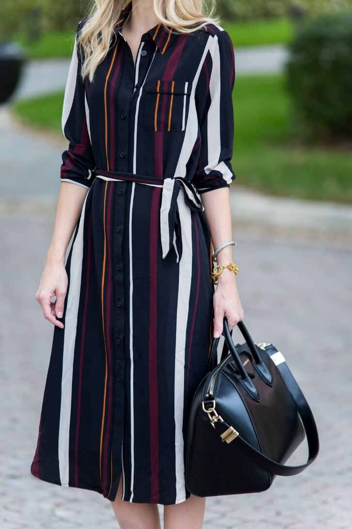 Working woman wearing a striped midi dress in three colors accent with a belt on the waist