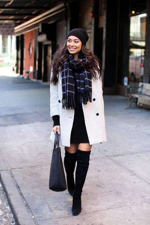 Warm yourself in a black beanie, cashmere scarf, and lovely white coat. Boots will provide you with extra warmth. #highboots #winteroutfits