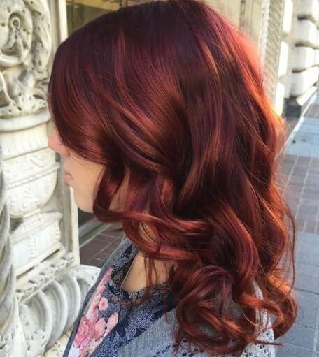Make your red hair curls more intense with lovely auburn highlights.