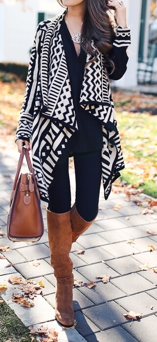 Woman wearing black leggings, long black top, Aztec print poncho, brown leather handbag and brown boots