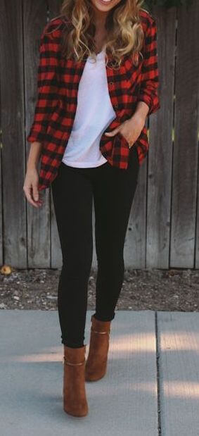 Woman on the sidewalk wearing black skinny jeans, white T-shirt, plaid shirt and brown boots