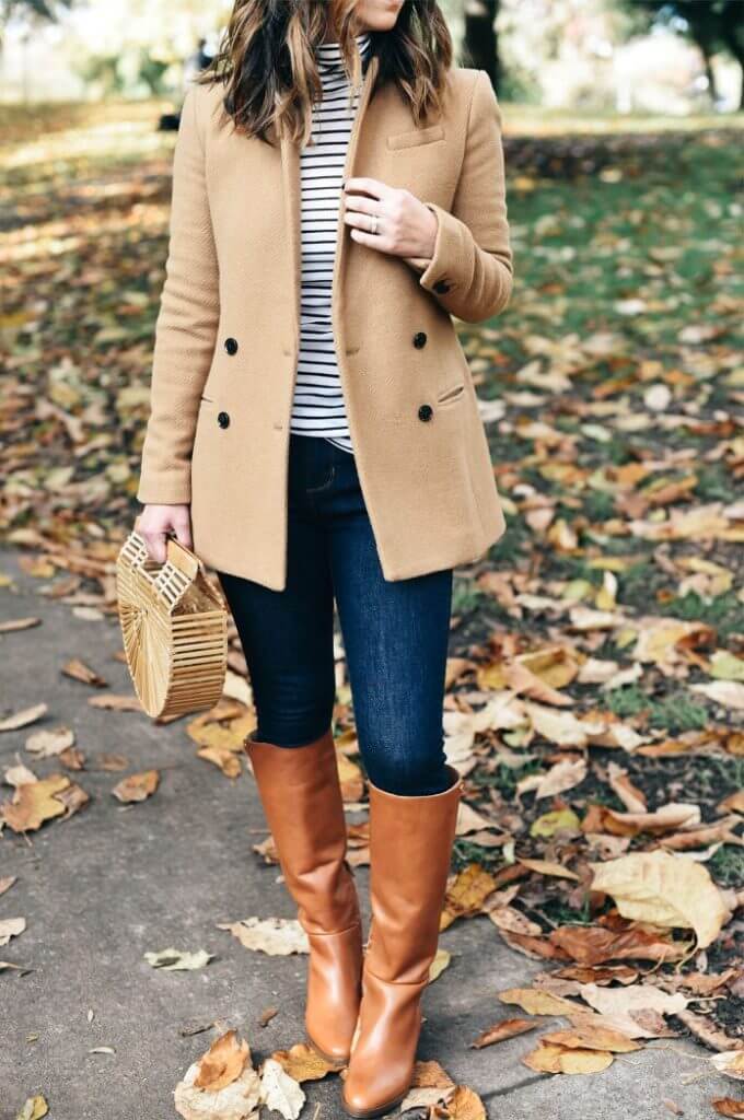 Woman wearing blue skinny jeans, striped top, camel blazer and brown boots