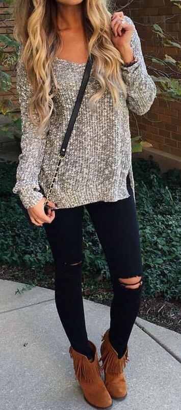 Woman wearing ripped black skinny jeans, gray sweater and brown boots