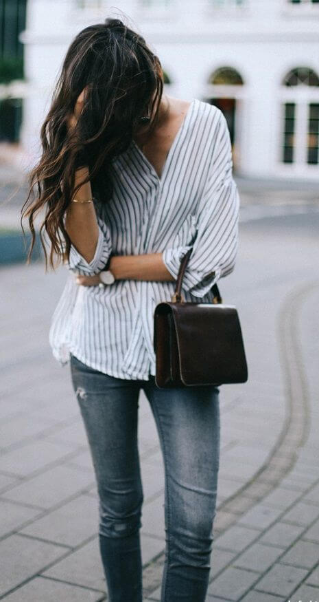 Woman on the sidewalk in striped shirt and blue jeans. An easy-going weekend uniform of stripes and blue denim.
