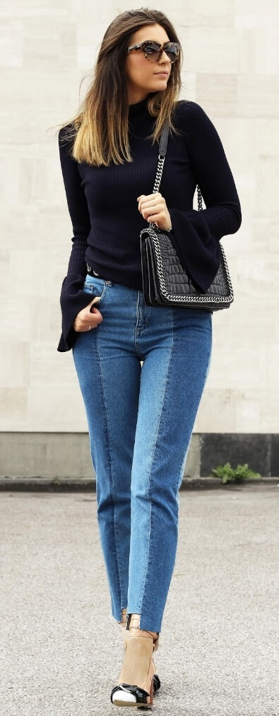 Fashionable woman is wearing patchwork denim jeans and a turtleneck sweater with bell sleeves. The season's trendiest styles go together ever-so-well: patchwork denim and subtle bell sleeves.