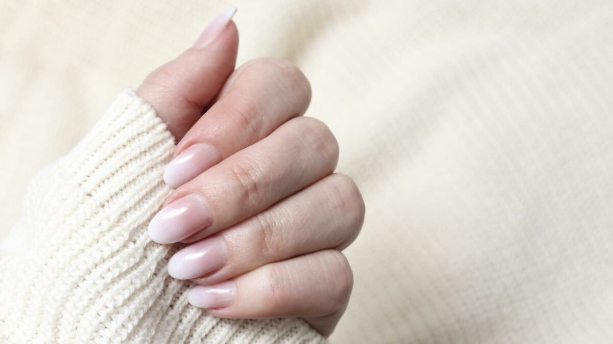 Women's hands with a beautiful delicate white manicure close-up. Female nail manicure. Luxurious design of nails on the beautiful hands of a woman