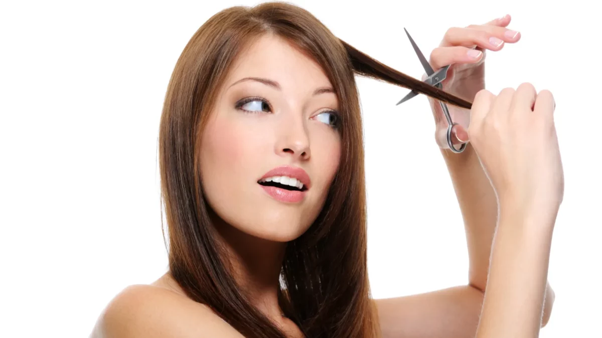 Brunette girl cutting hair with scissors