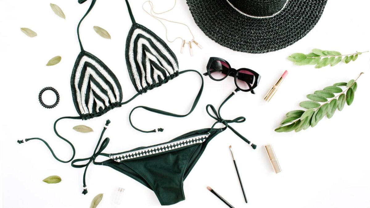 female summer bikini swimsuit accessories collage on white with hat, green branches, necklace and sunglasses. flat lay, top view