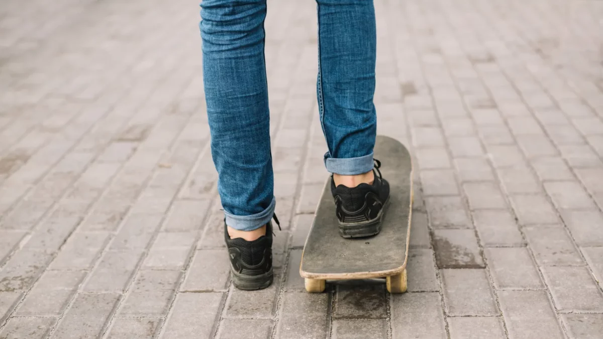 Teenager skateboarding, wearing cuffed jeans