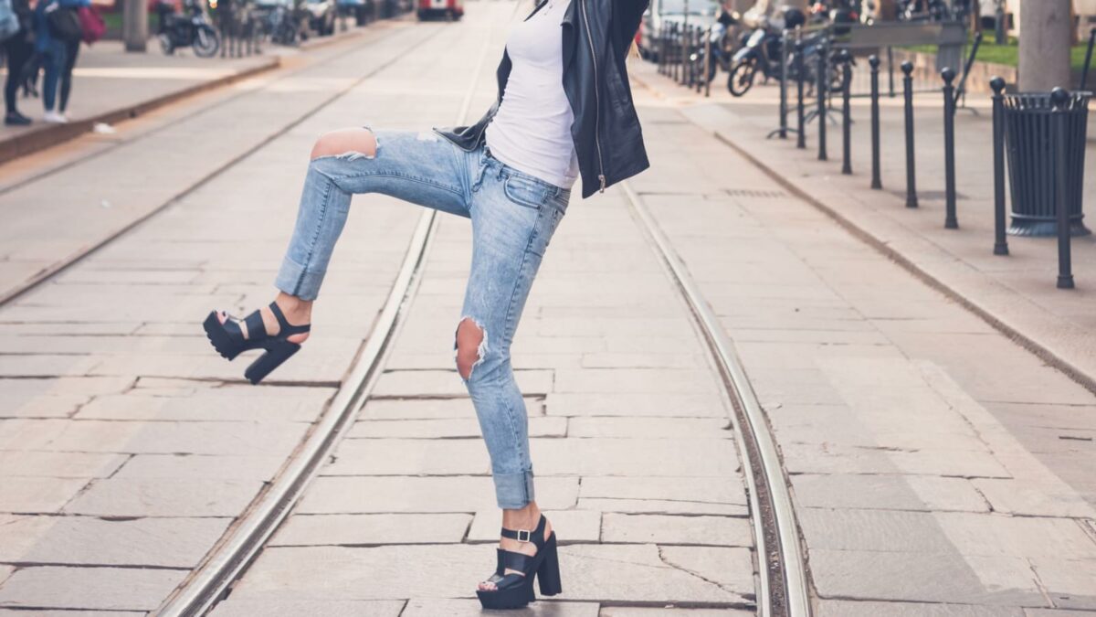 Girl wearing ripped jeans and leather jacket posing in the city streets