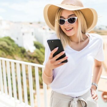 Attractive young woman typing on phone on terrace on beach view background.