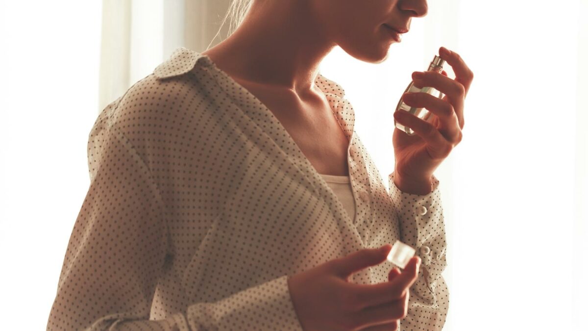 Stylish woman in blouse with bottle of favorite perfume. Fashion, beauty and style