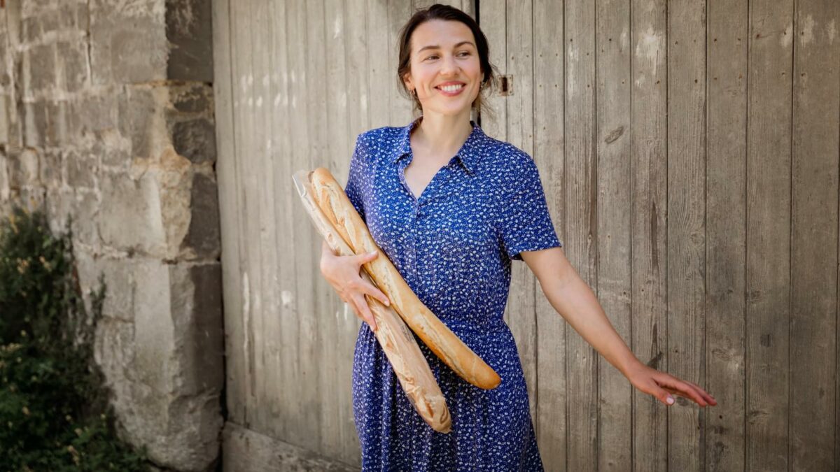 Young pretty woman standing with french baguettes in her hands in the countryside