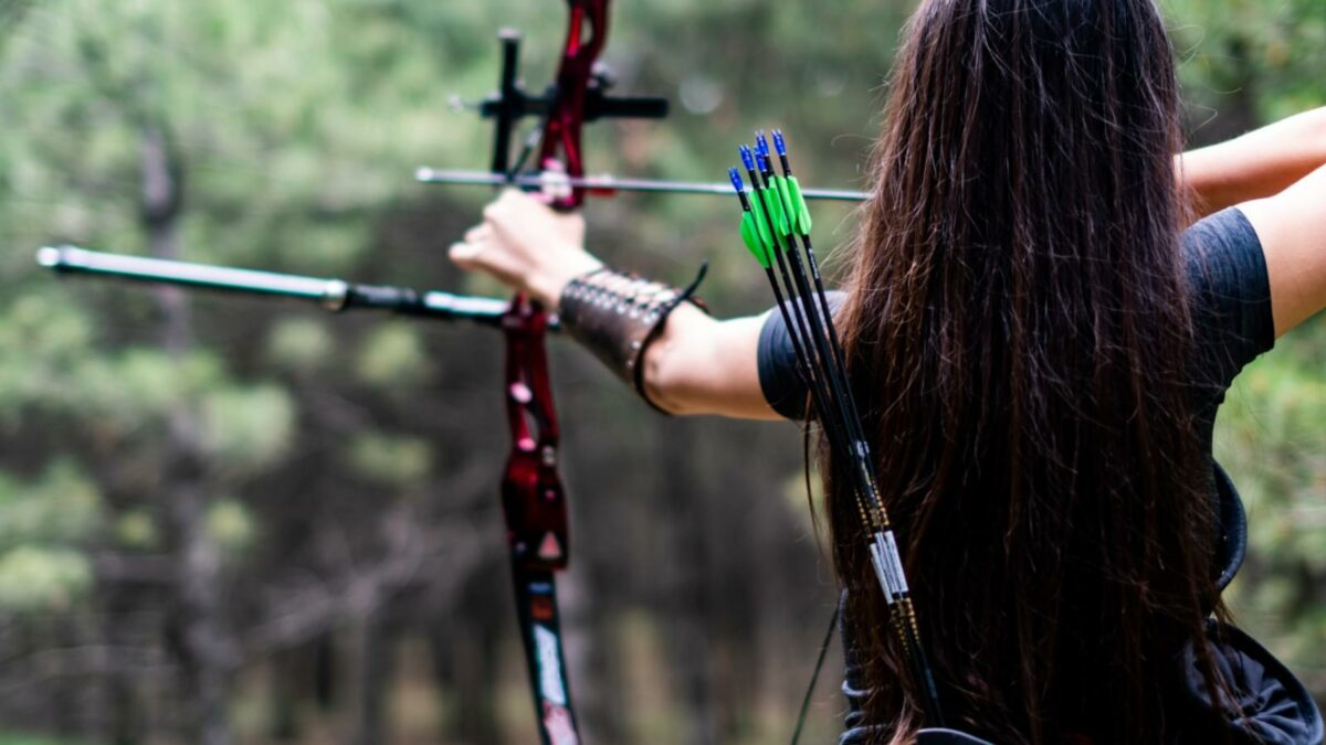 Athletic woman aiming with bow arrow