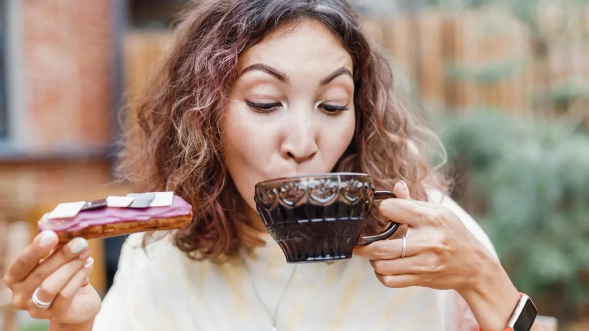 Happy woman eating delicious tasty eclair