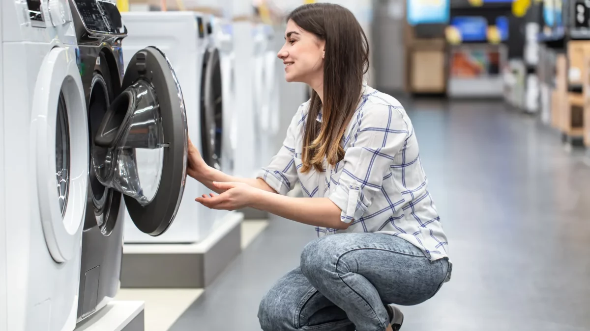 Woman stores jeans into a washing machine