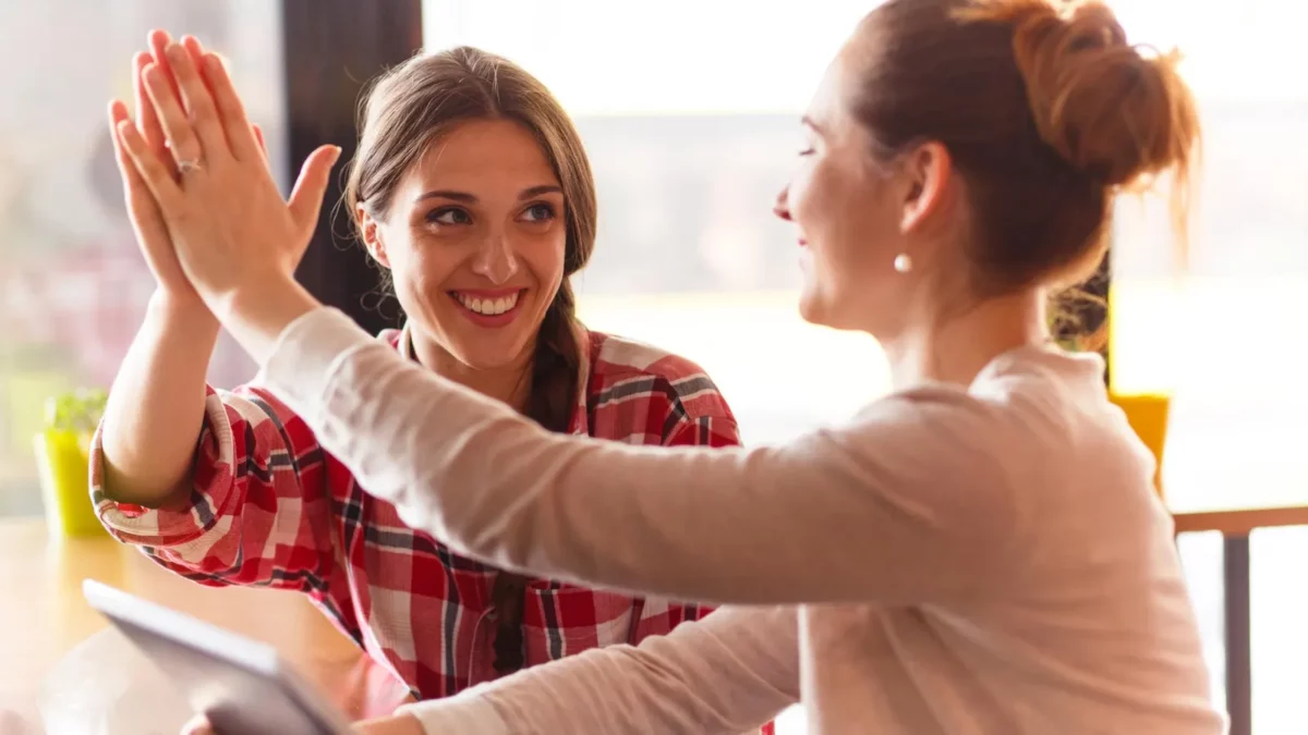 Women giving high five talking about every day things