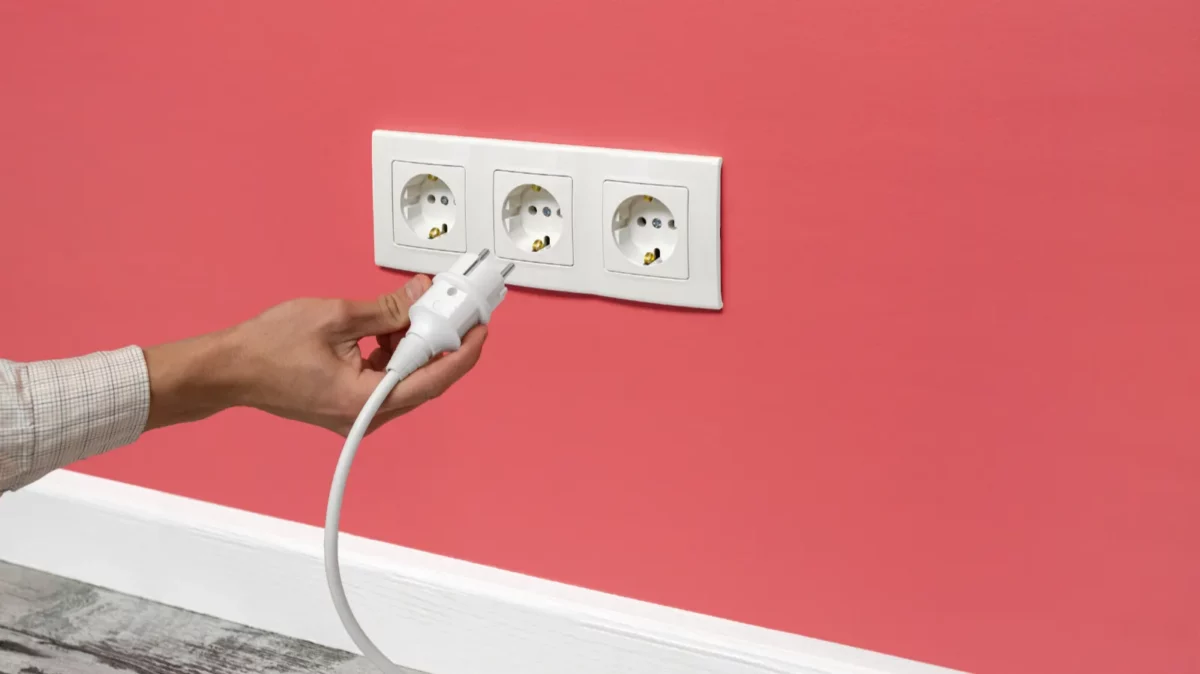 Man plugging cord into electrical outlet