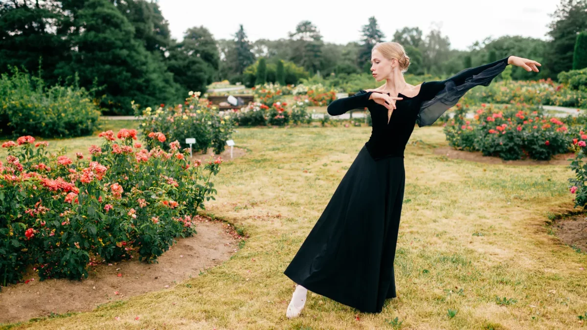 Ballerina in black dress posing in summer park