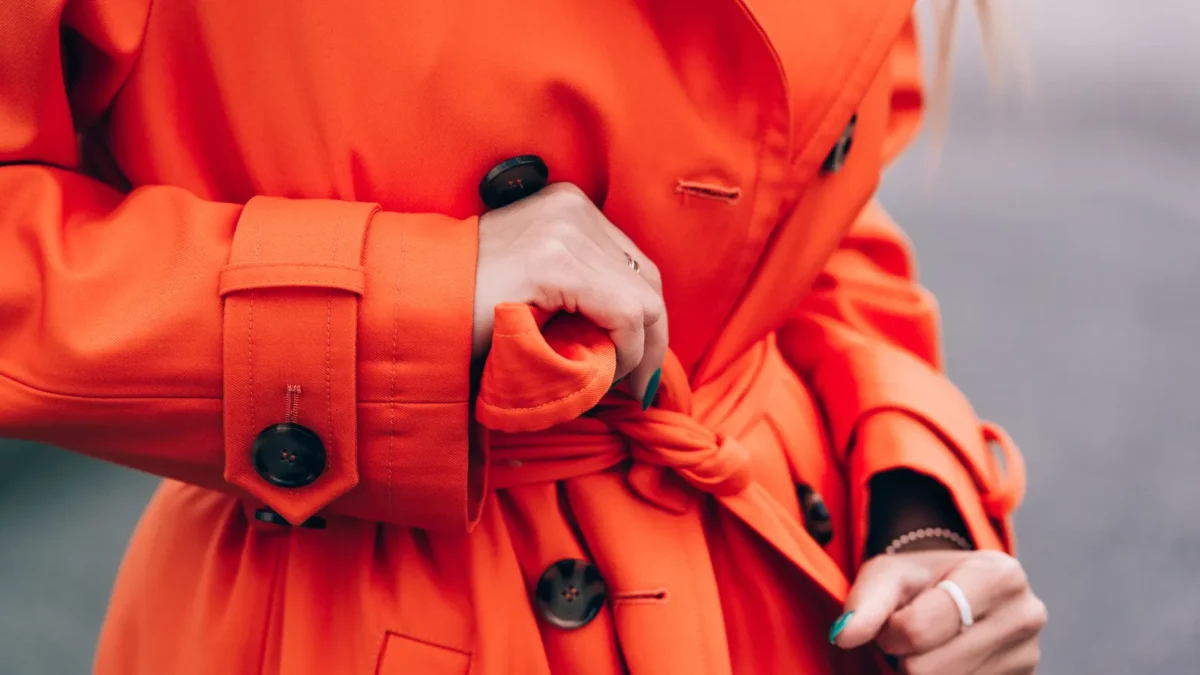 Fashionable woman wearing orange trench coat with knot