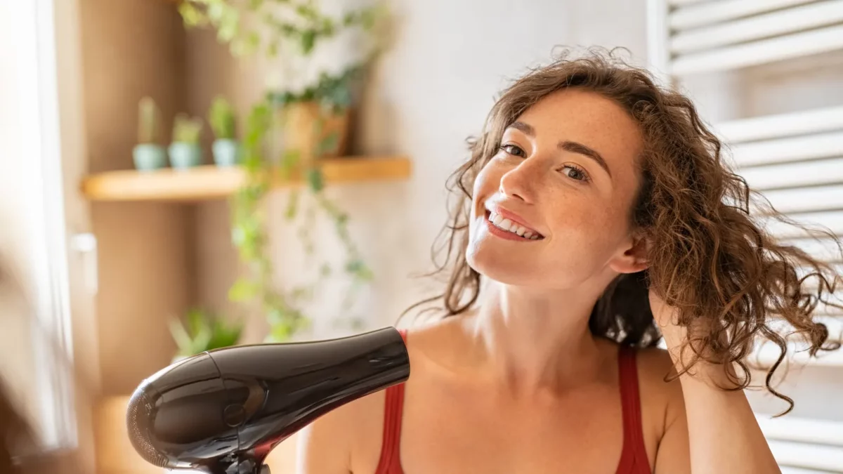 Girl using a hair dryer and smiling