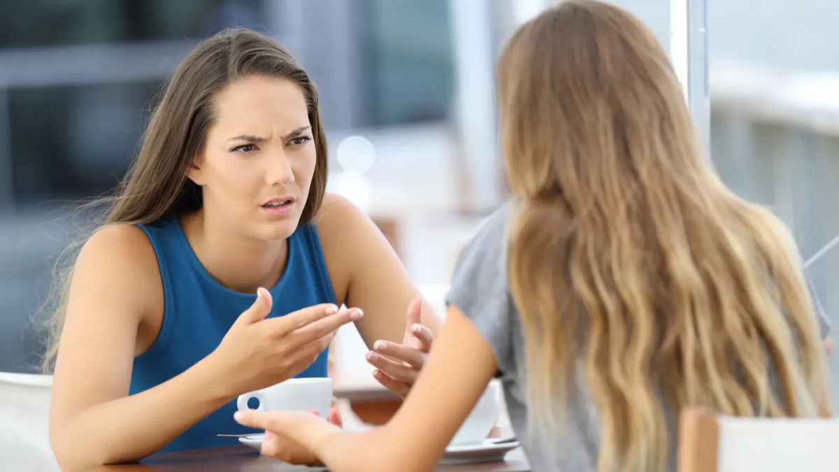 Two angry girls talking seriously sitting in a coffee shop