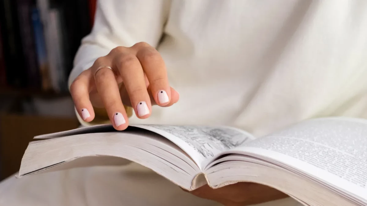 Woman with perfect beige manicure holding book
