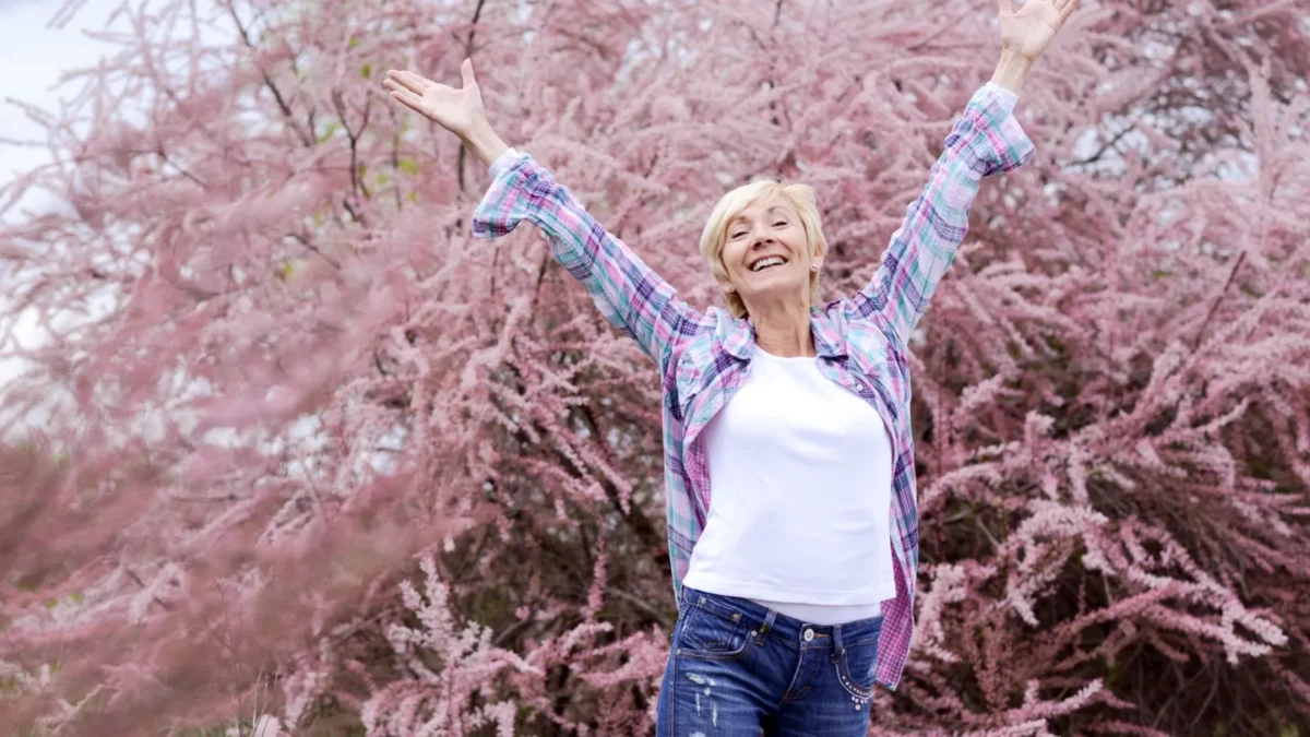 Middle aged woman in jeans smiling outdoors