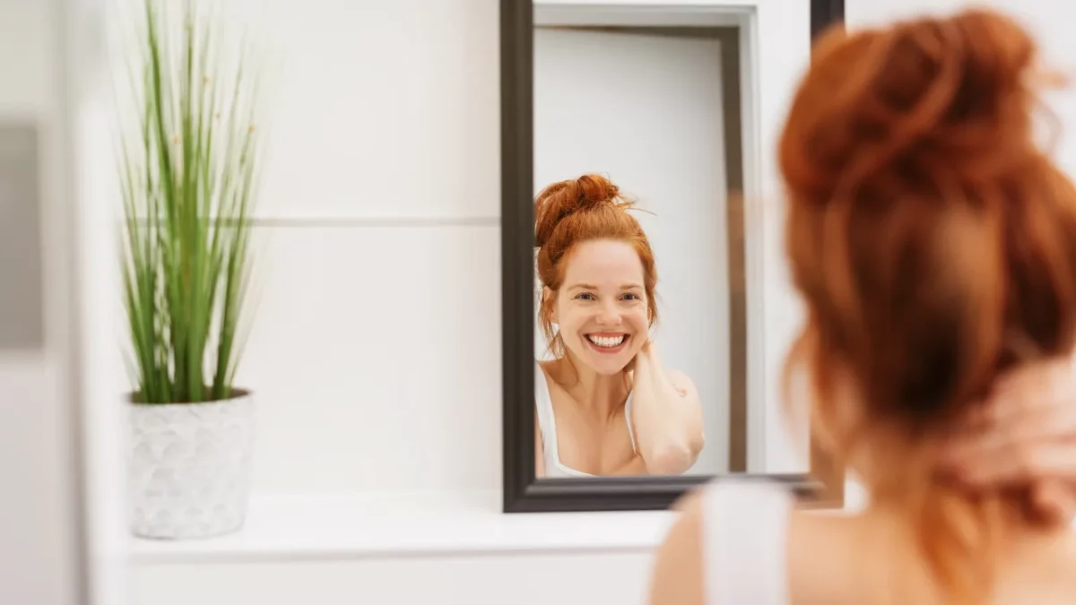 Redhead woman looking at the bathroom mirror