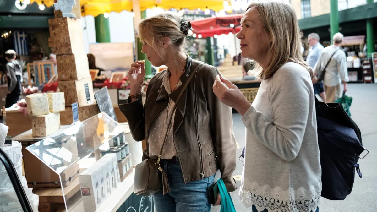 Two senior women friends enjoying shopping cheese in a street market