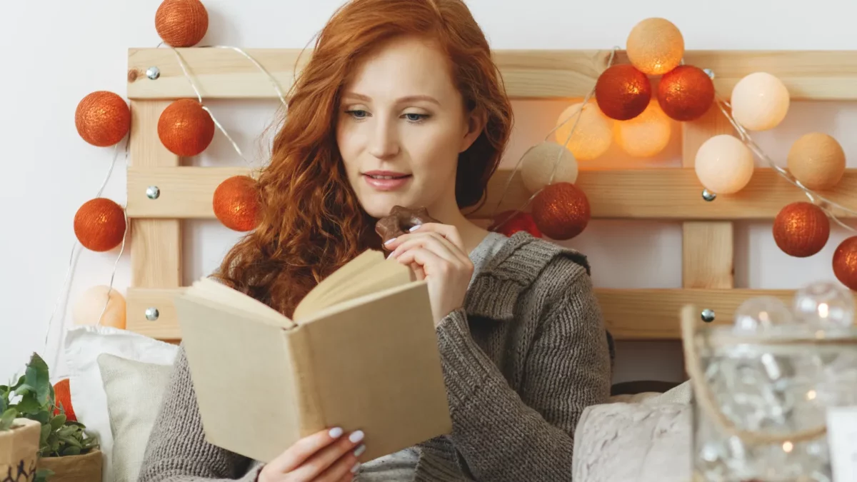 Woman eating chocolate while reading a book