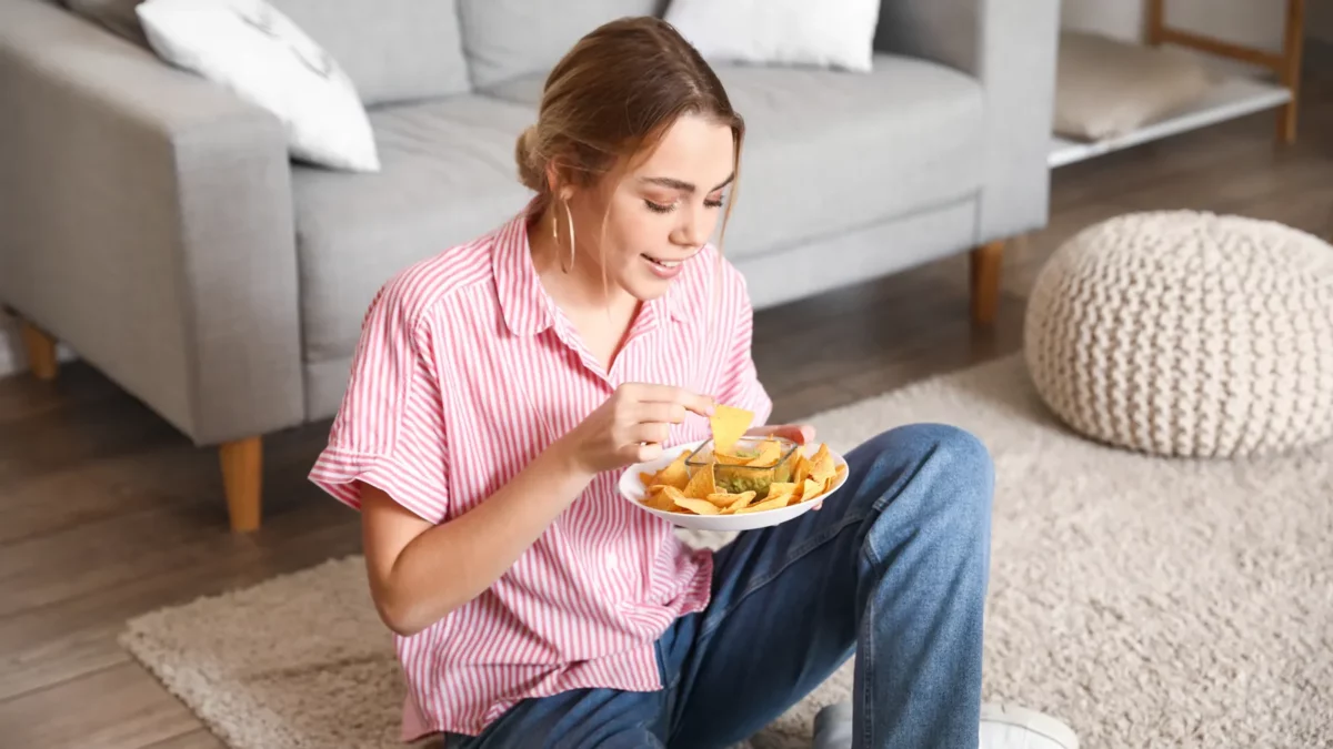 Woman eating tasty nachos at home