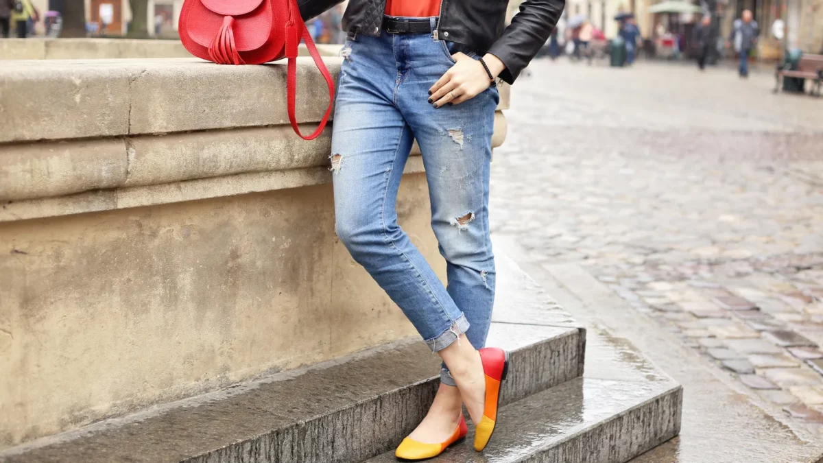 Woman in blue ripped jeans and colored ballet flats