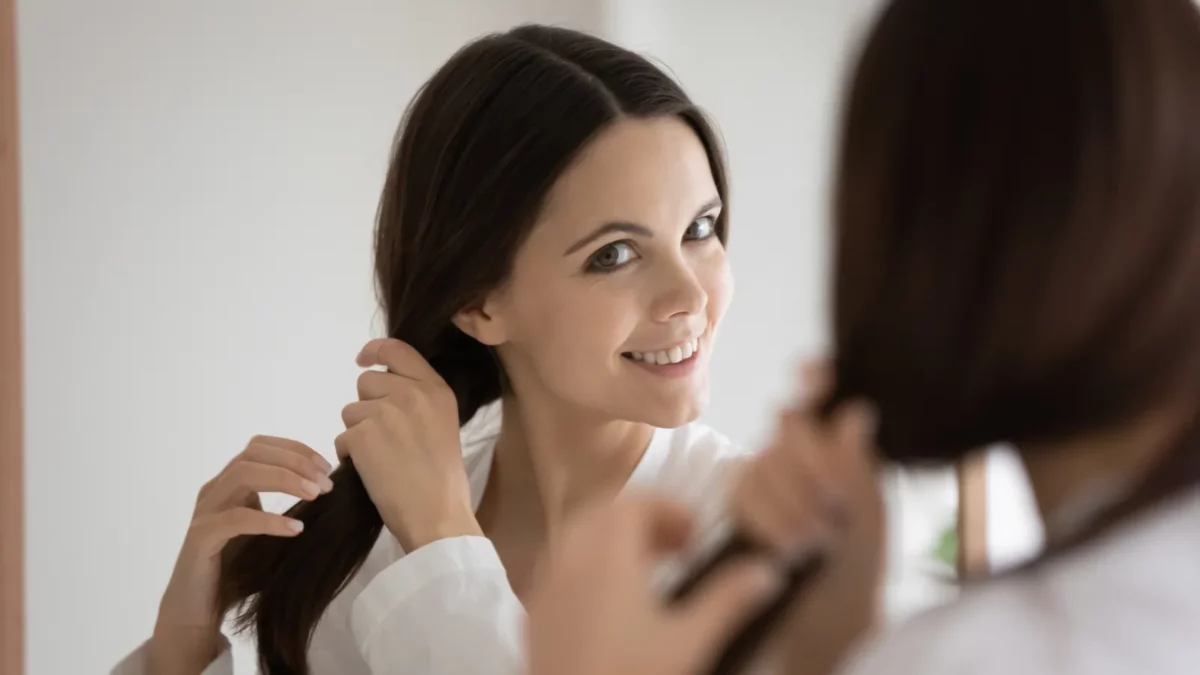 Woman looking into the mirror satisfied with healthy thick hair