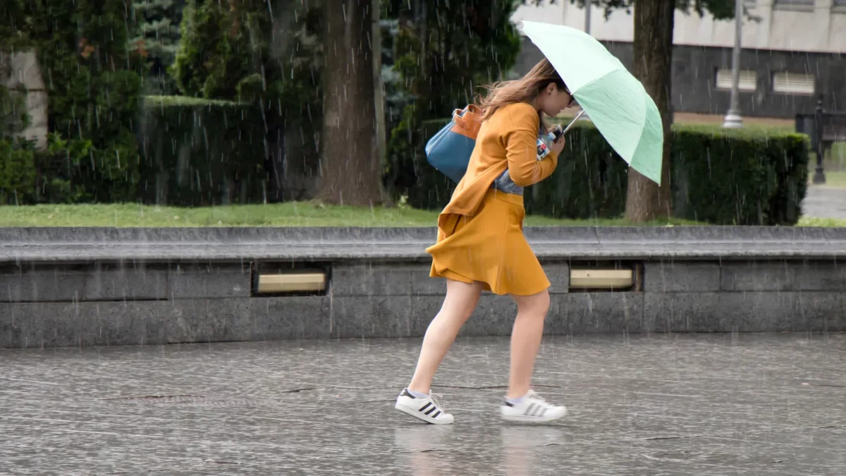 Woman running under umbrella in the rain