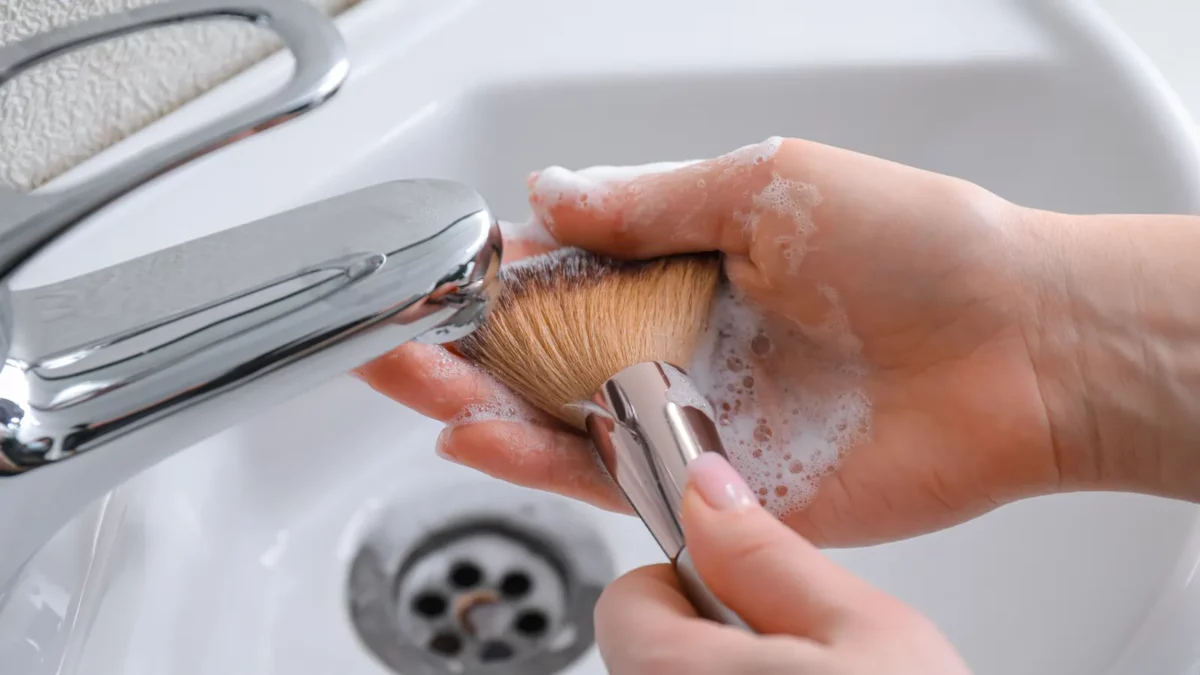 Woman washing makeup brush under water