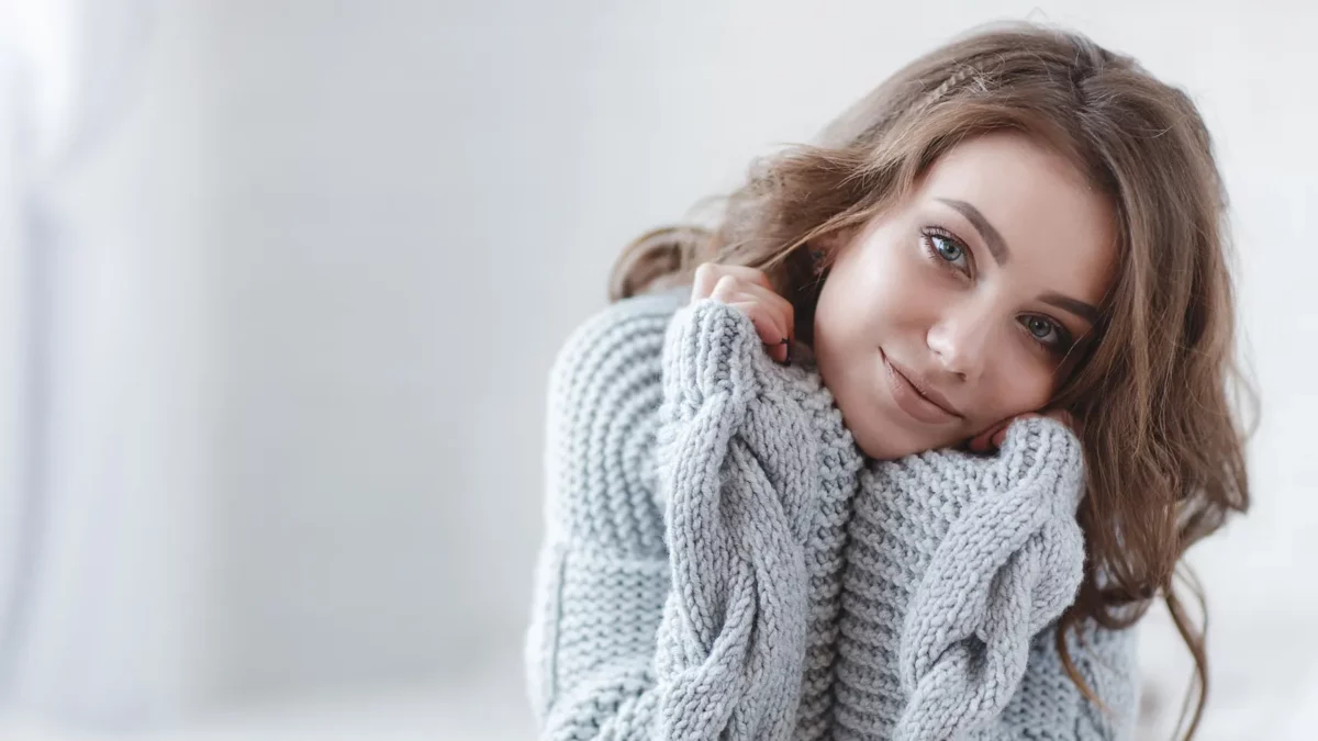Young beautiful woman in warm knitted clothes at home