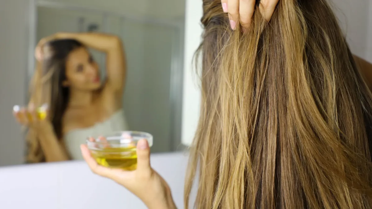 Young woman applying olive oil mask on hair