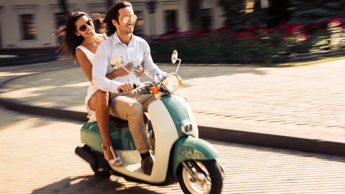Cheerful young couple riding a scooter